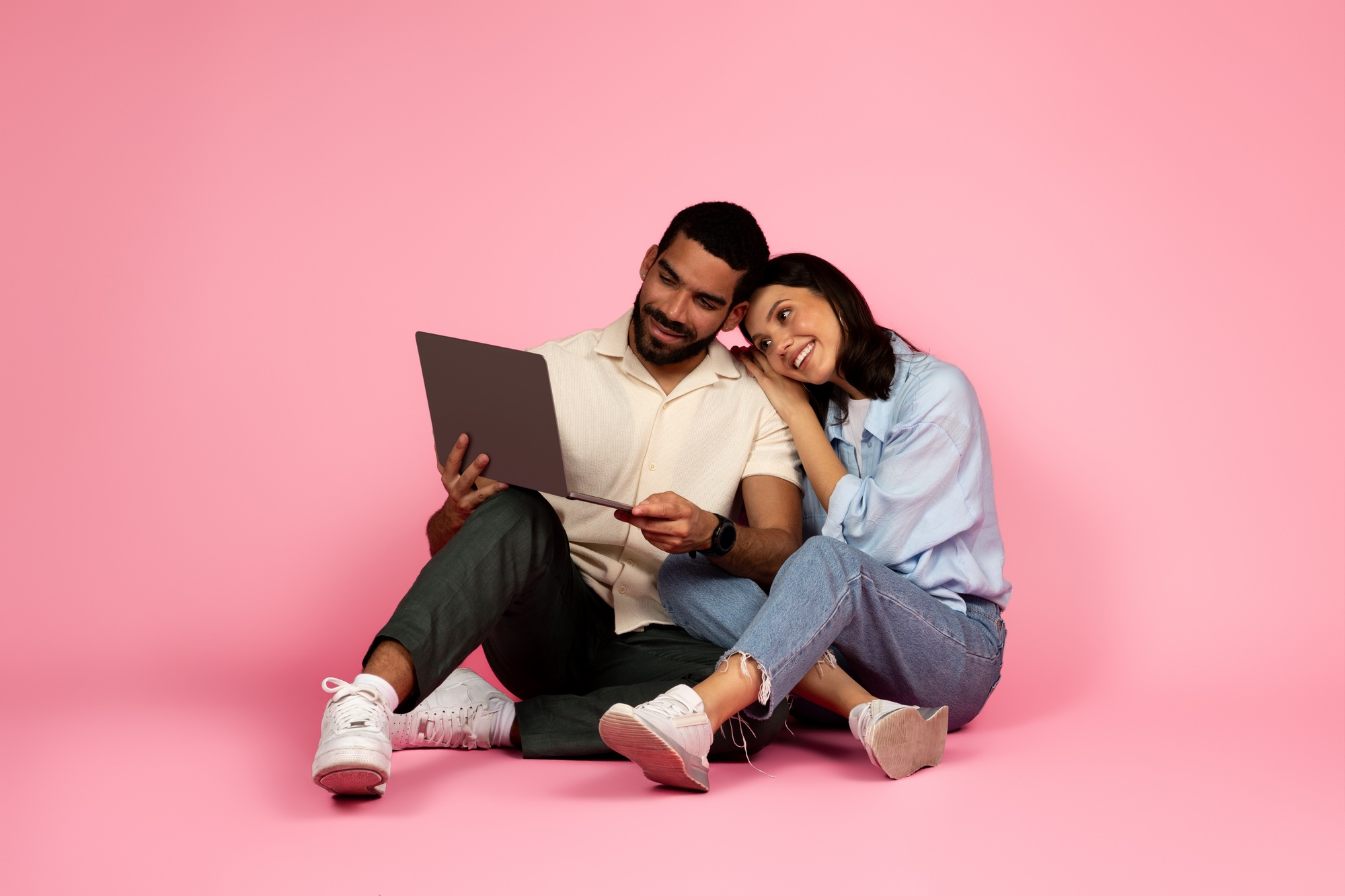 happy man and woman sitting on floor, watching movie online