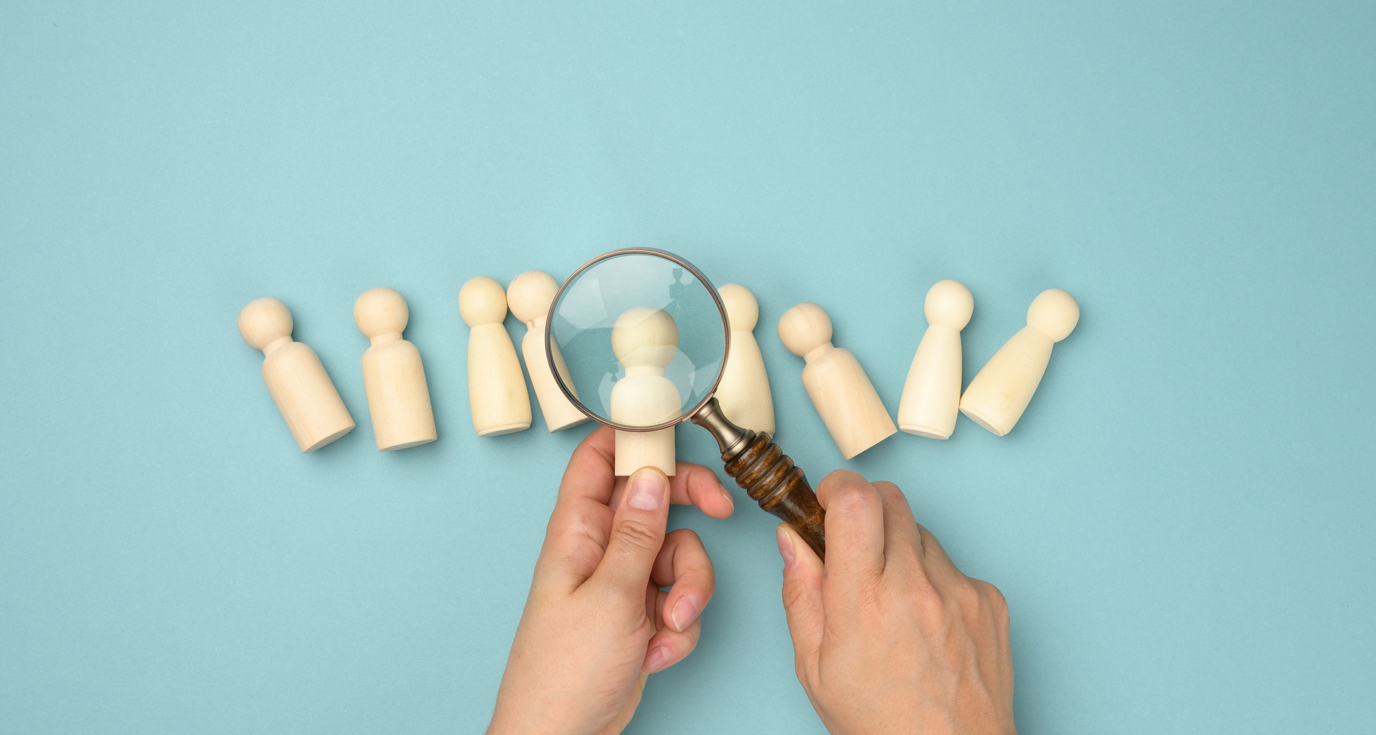 When AI Recruiters Go Wrong on New Automated Hiring Tools wooden men and a magnifying glass on a blue background. recruitment concept