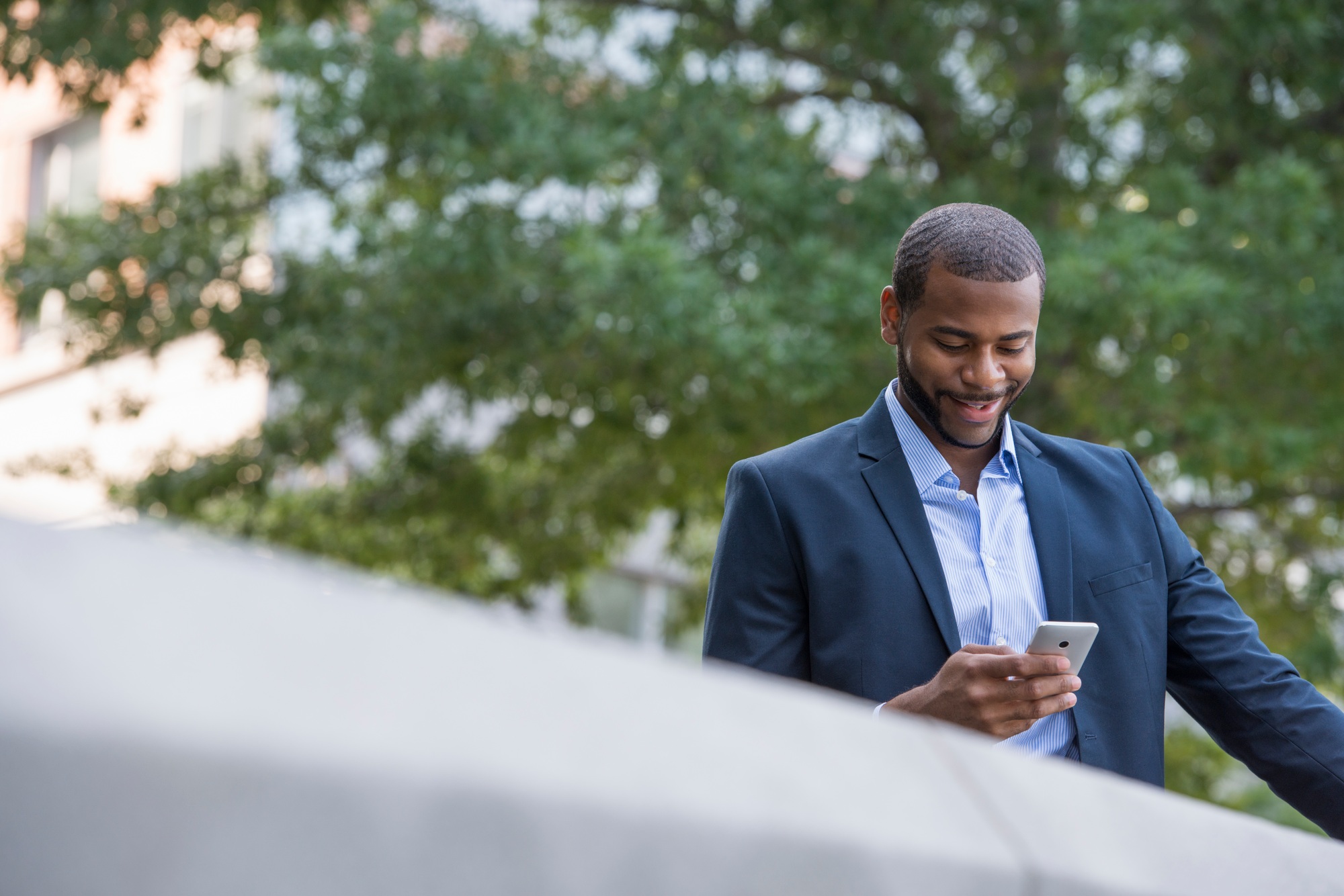 a man in a blue jacket and open collared shirt using a smart phone.