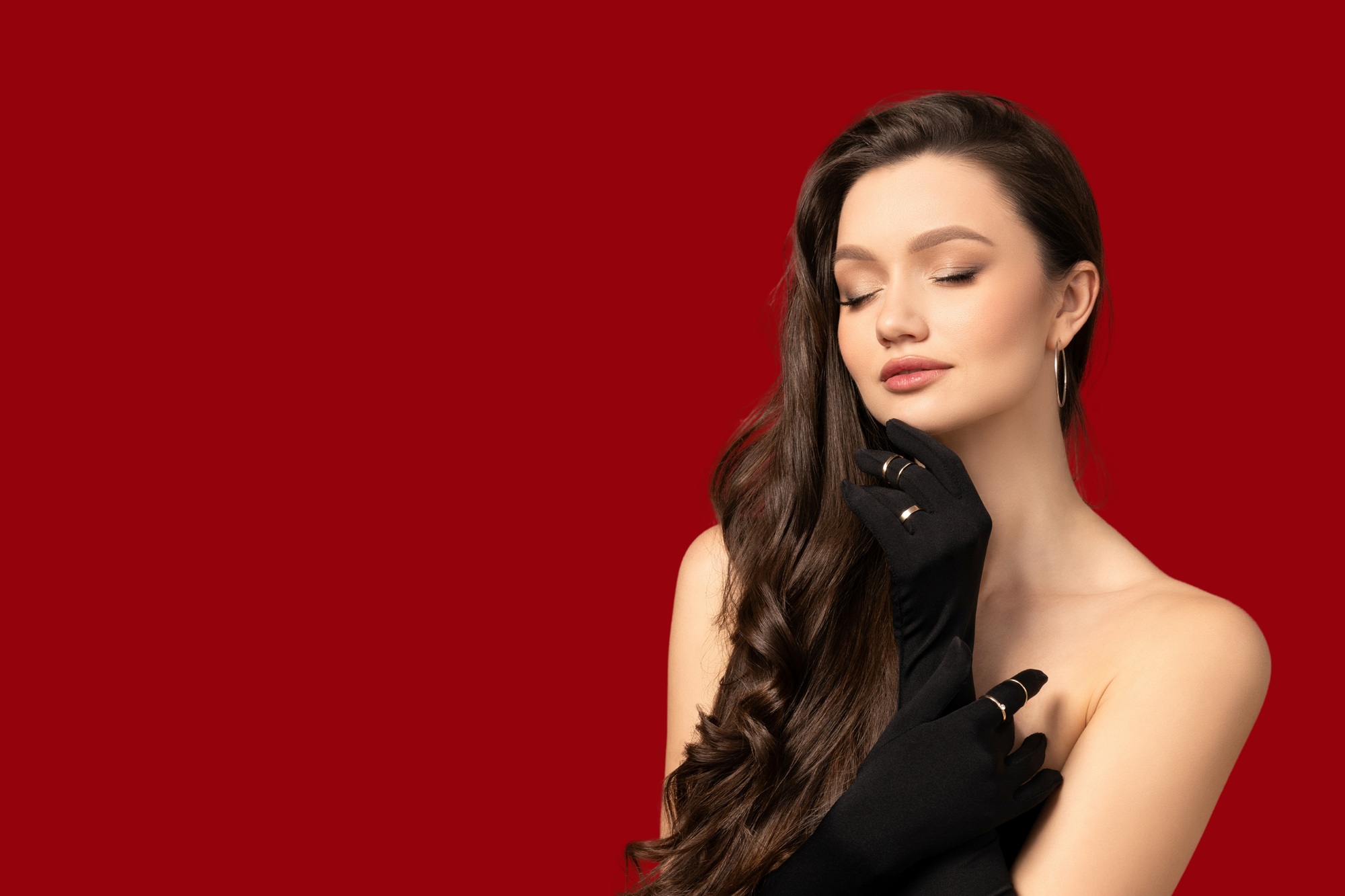 portrait of a beautiful, young girl in a black outfit, on a red background.