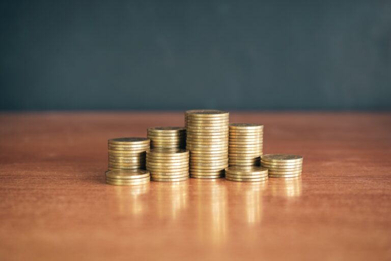 Stack of golden money coin on wood desk with black background. Business and financial concept.