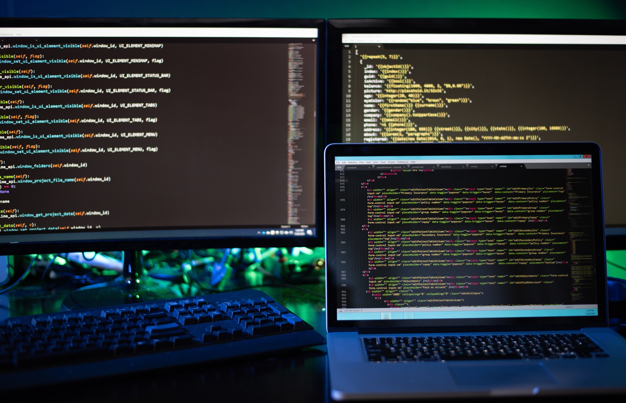 three computer screens with computer programming code