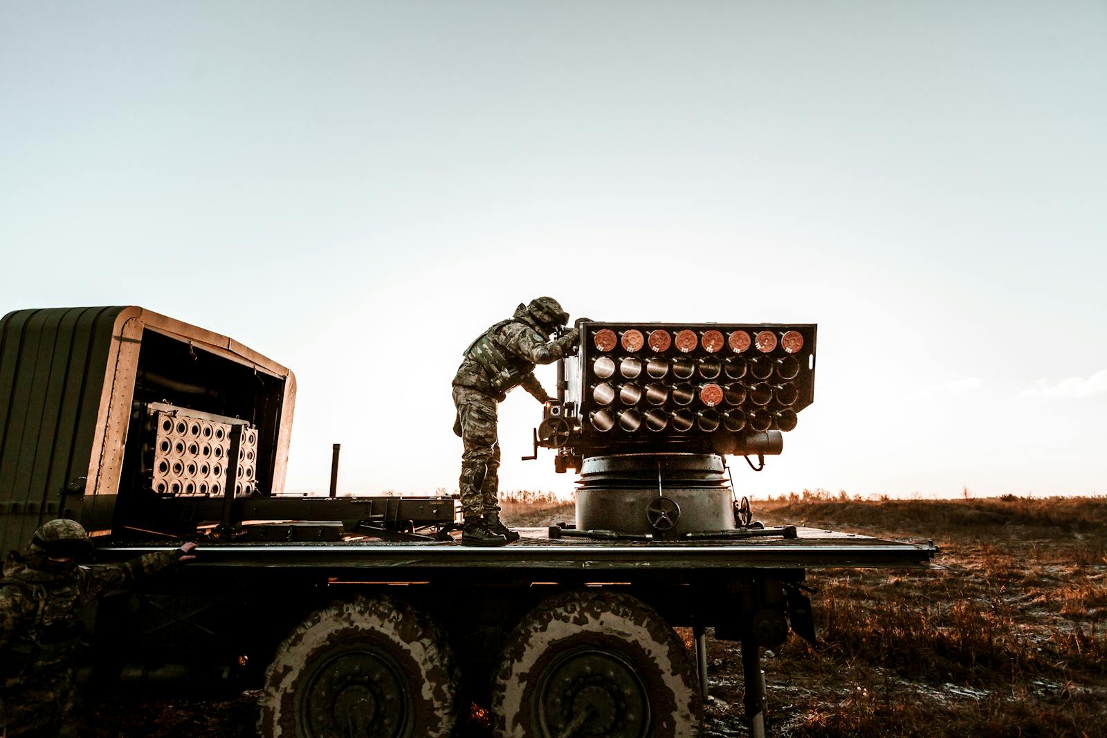 🤖 The New Rules of War on AI Rewriting Conflict Soldier adjusting artillery on military truck in an open field under clear sky.