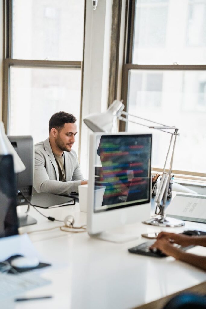 The Truth About Mass Layoffs and A.I. A young man working at a desktop computer in a bright, modern office environment.