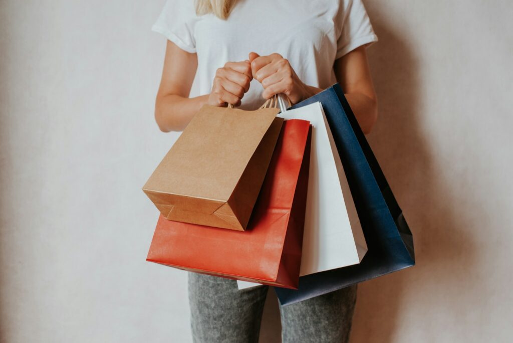 Woman holding shopping bags in front of white wall