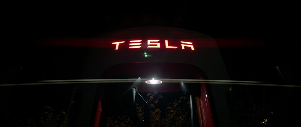 a neon sign that reads tesla above a building