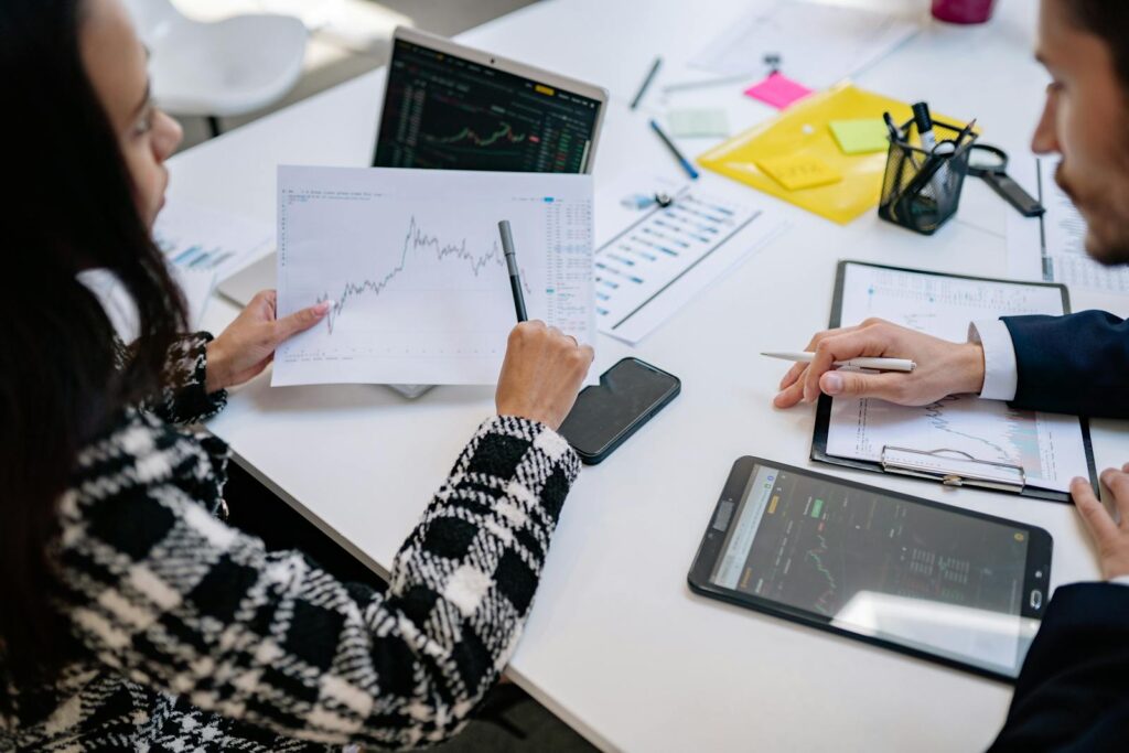Two colleagues analyzing financial graphs during a business meeting in a modern office setting.