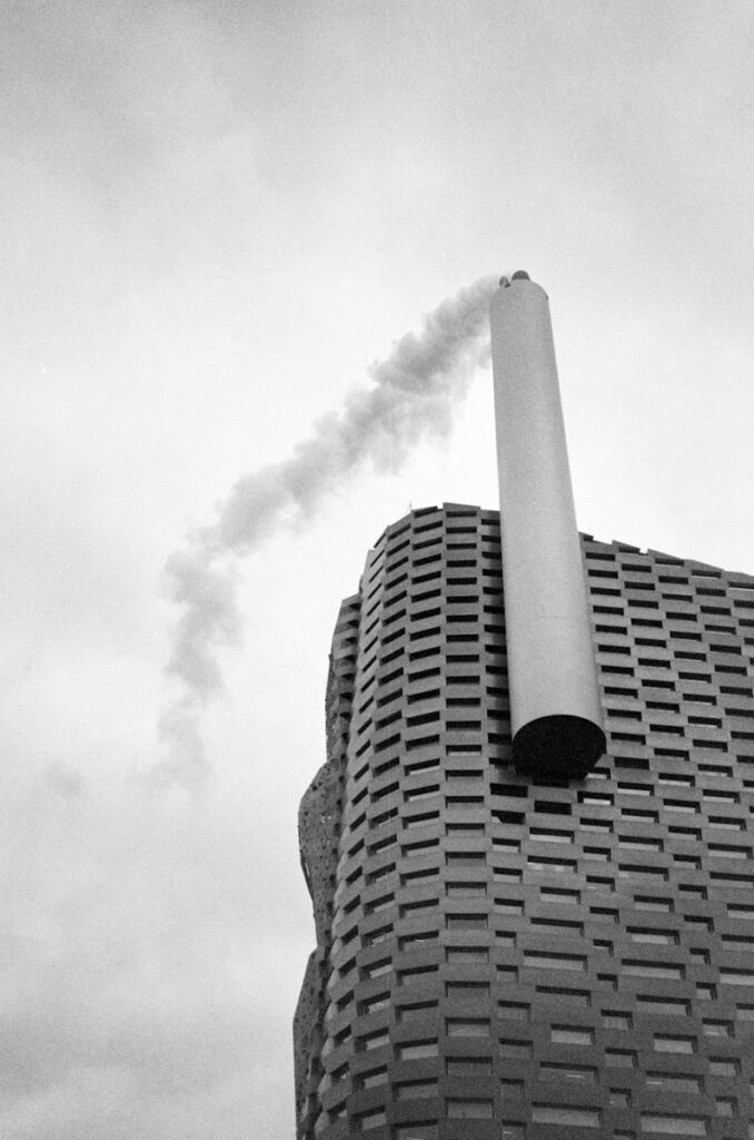 Smoke billows from a tall chimney on a building.