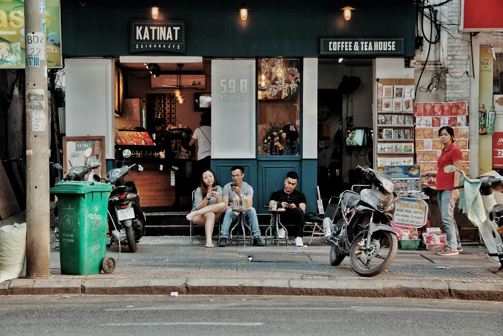 People sitting outside a coffee shop in an urban setting, enjoying drinks and conversation.