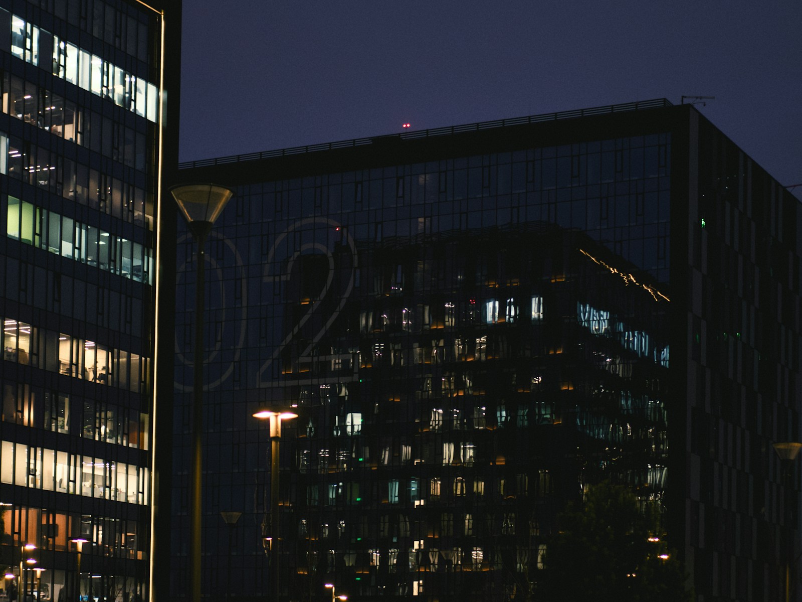 Modern office buildings at night with lit windows.