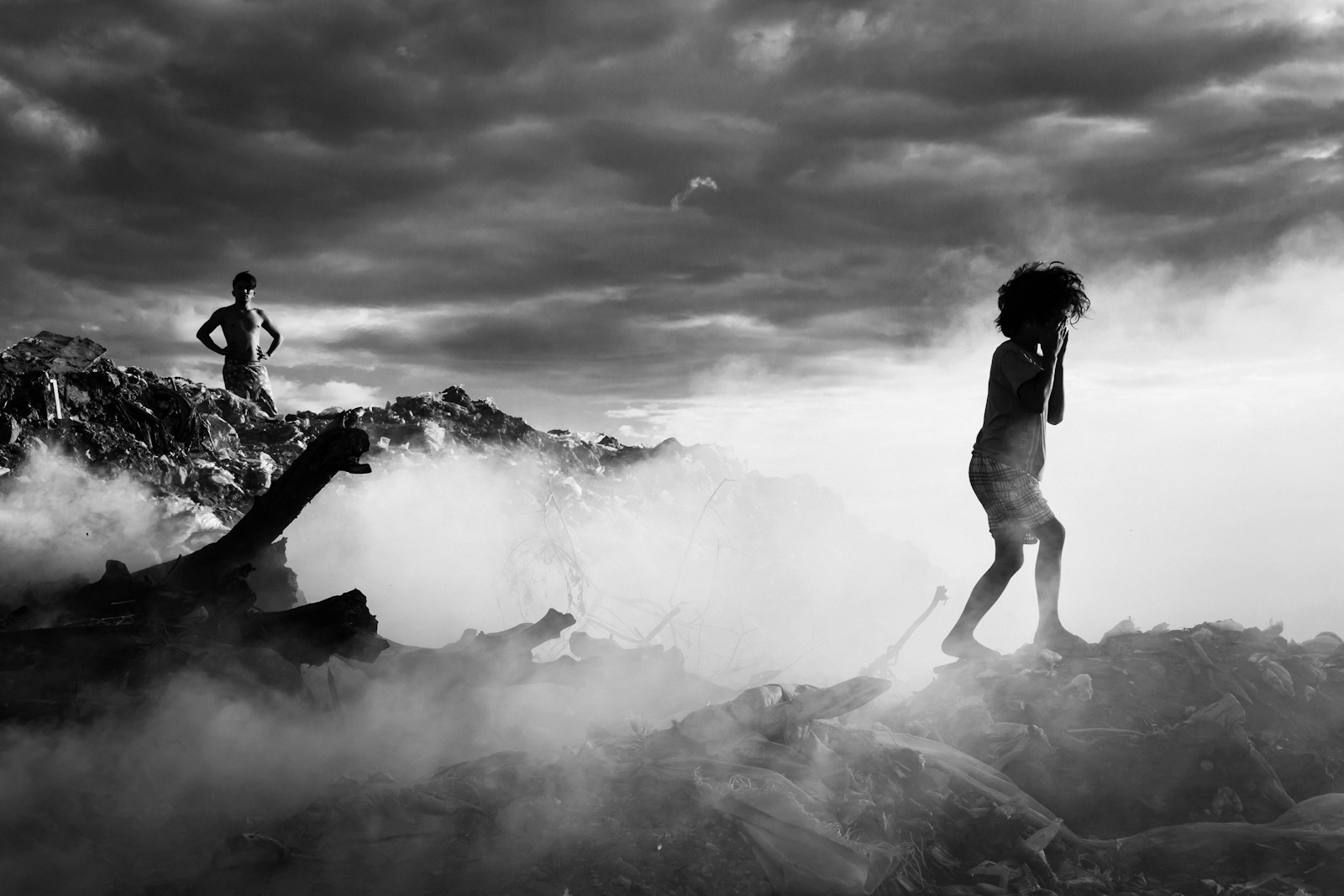 Two figures stand amidst smoke and debris