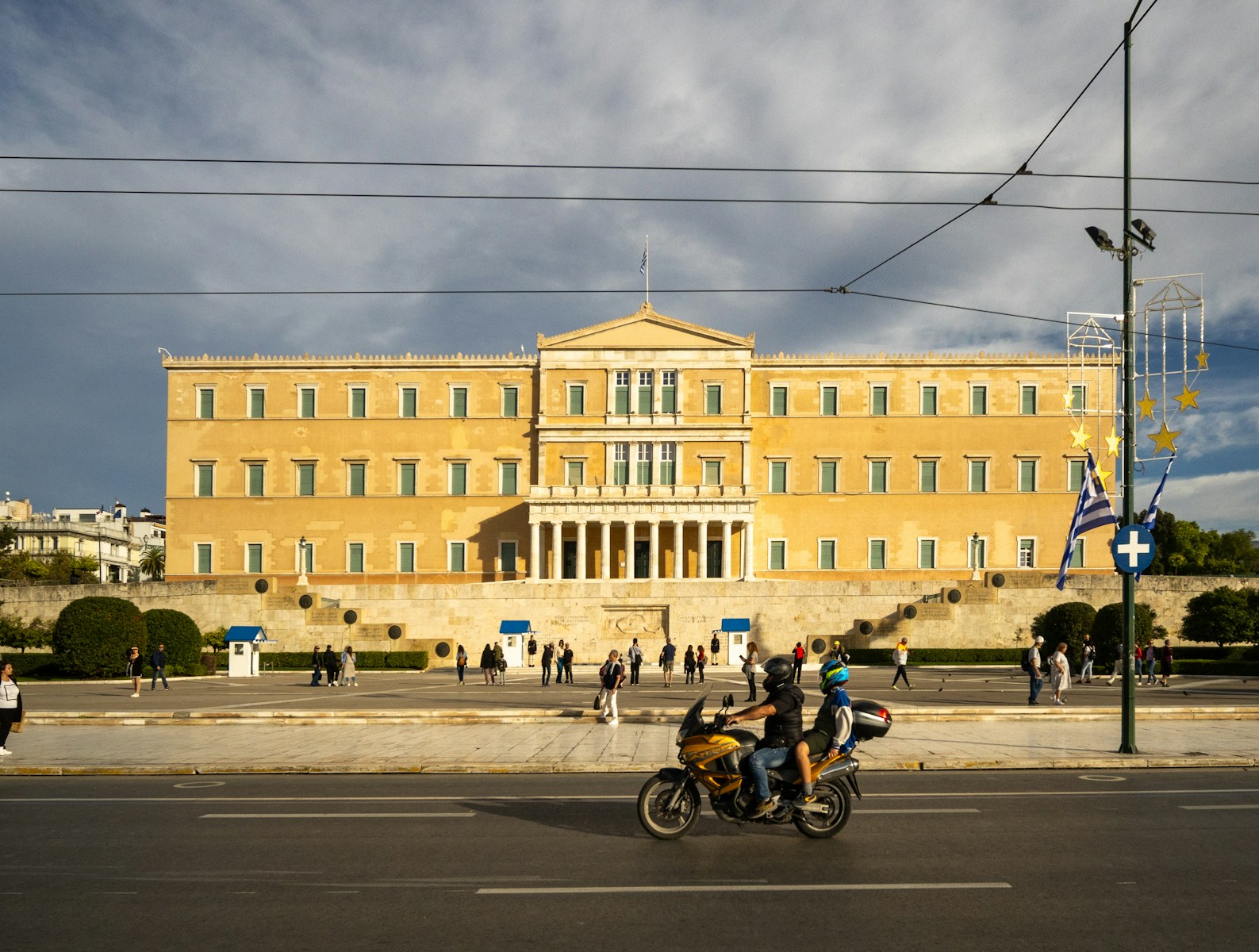 Two people riding a motorcycle in front of a building