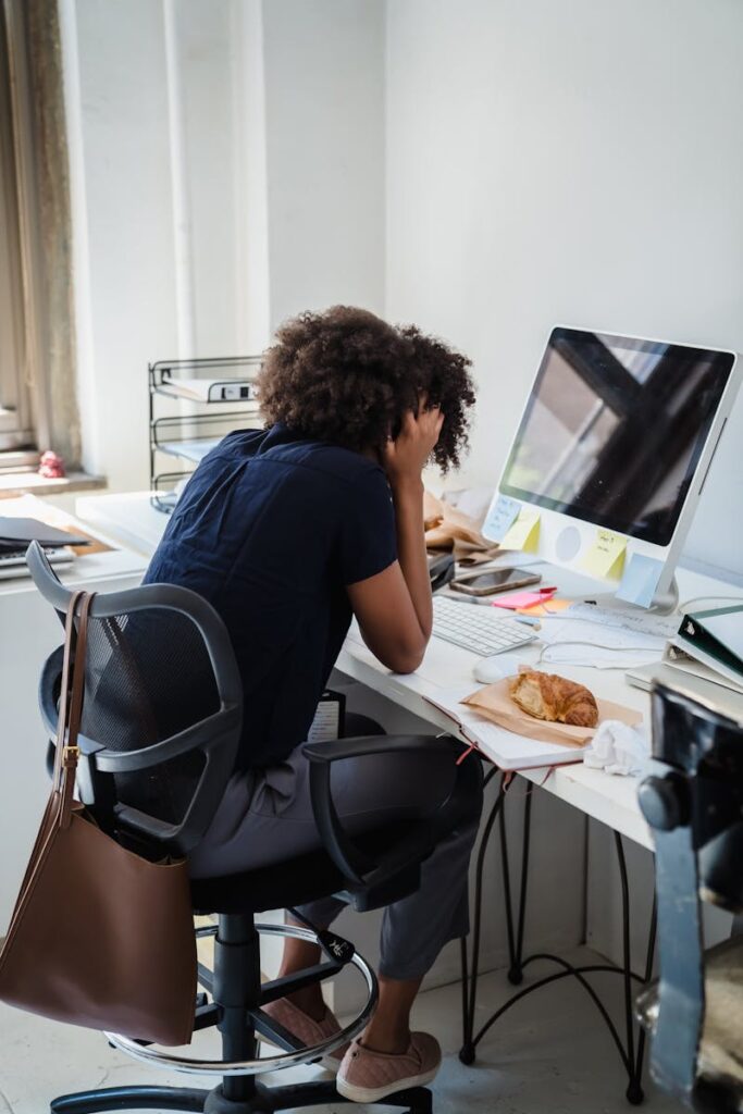 Businesswoman showing stress while working at her desk in an office setting.