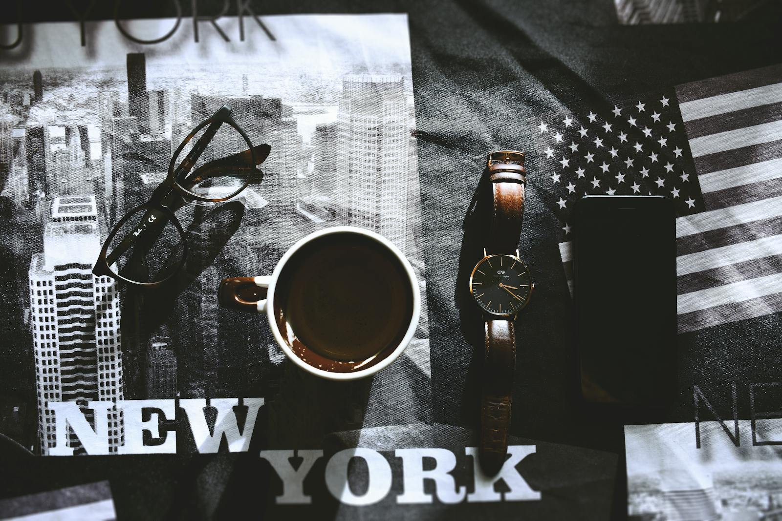 Why U.S. Government’s New “Tech Force” Change America Does AI Stylish flatlay showcasing a cup of coffee, wristwatch, eyewear, and phone on a New York themed background.