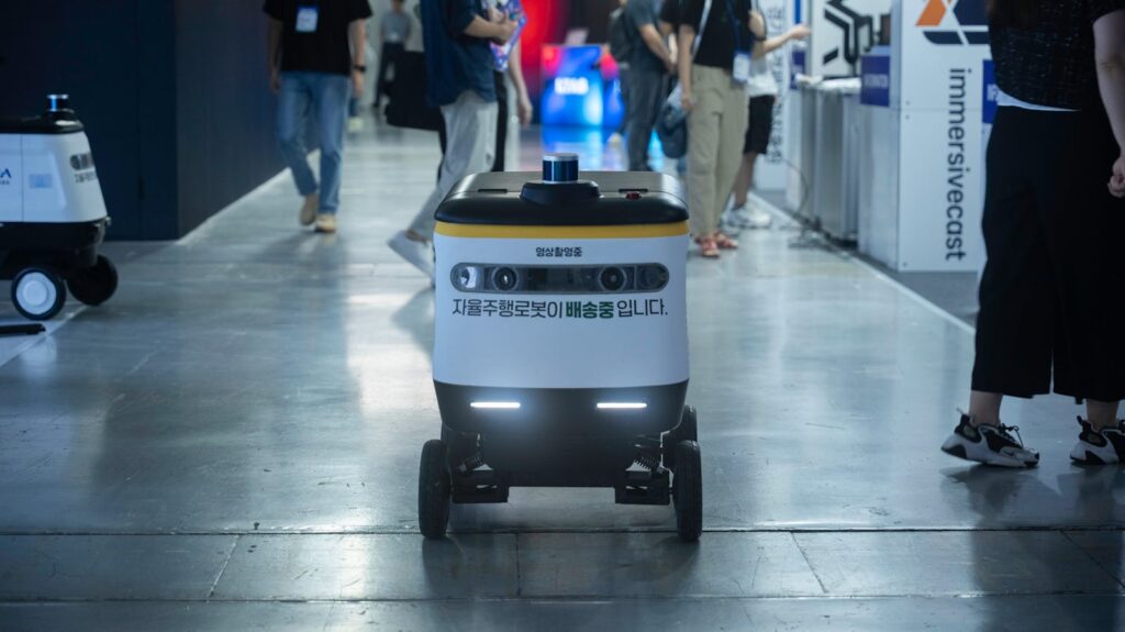 Autonomous delivery robot navigating indoors during a technology event.
