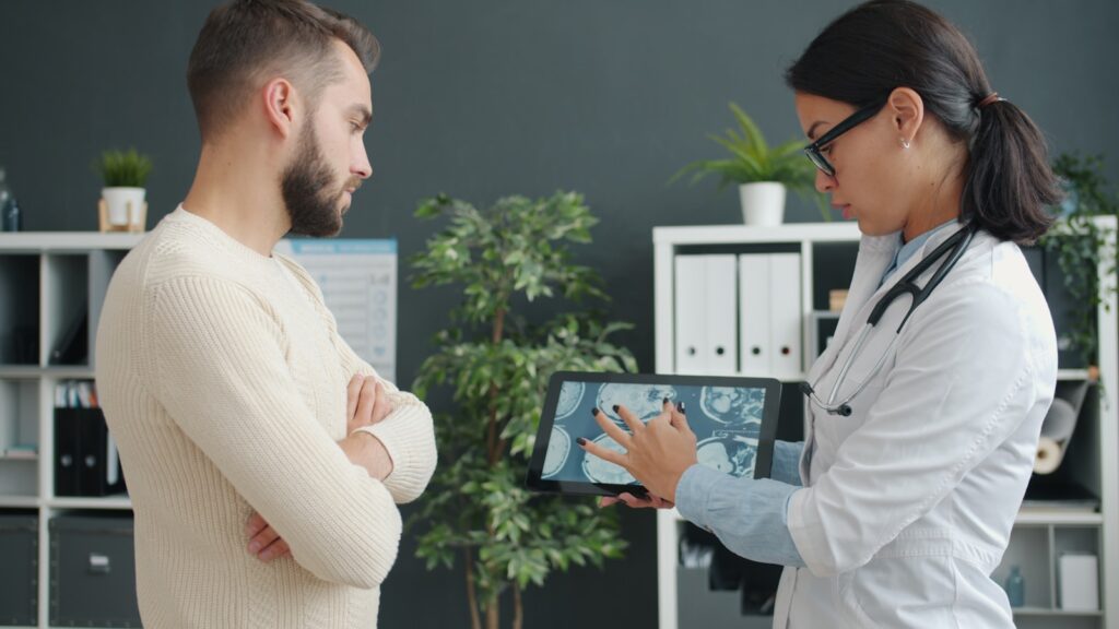 Doctor shows patient medical scan on tablet.