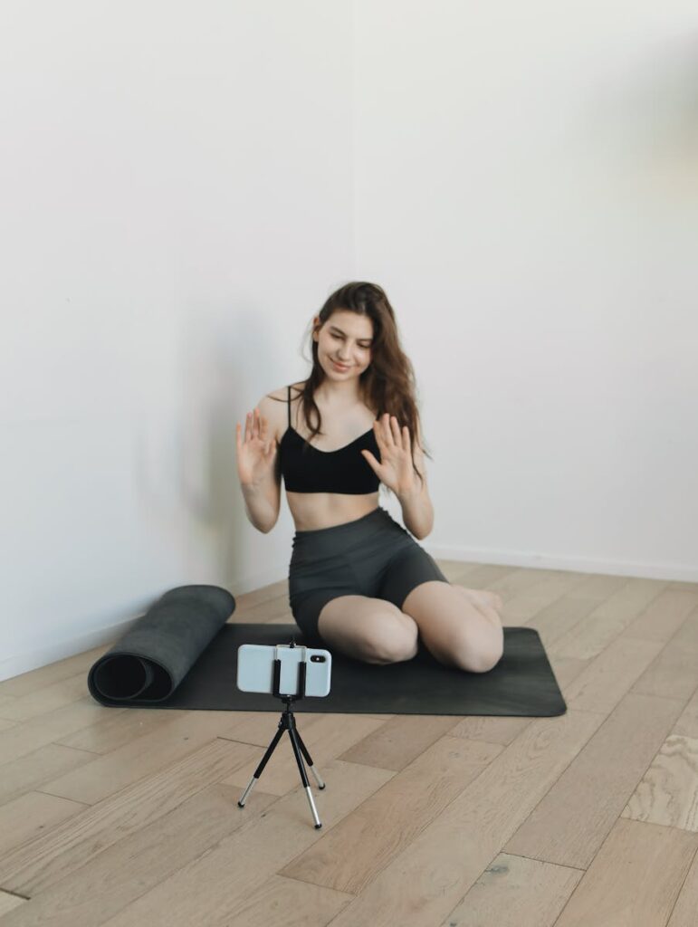 Why New Users Are Being Flooded With Low-Quality AI Content Woman on yoga mat recording a fitness video with her phone on a tripod at home.