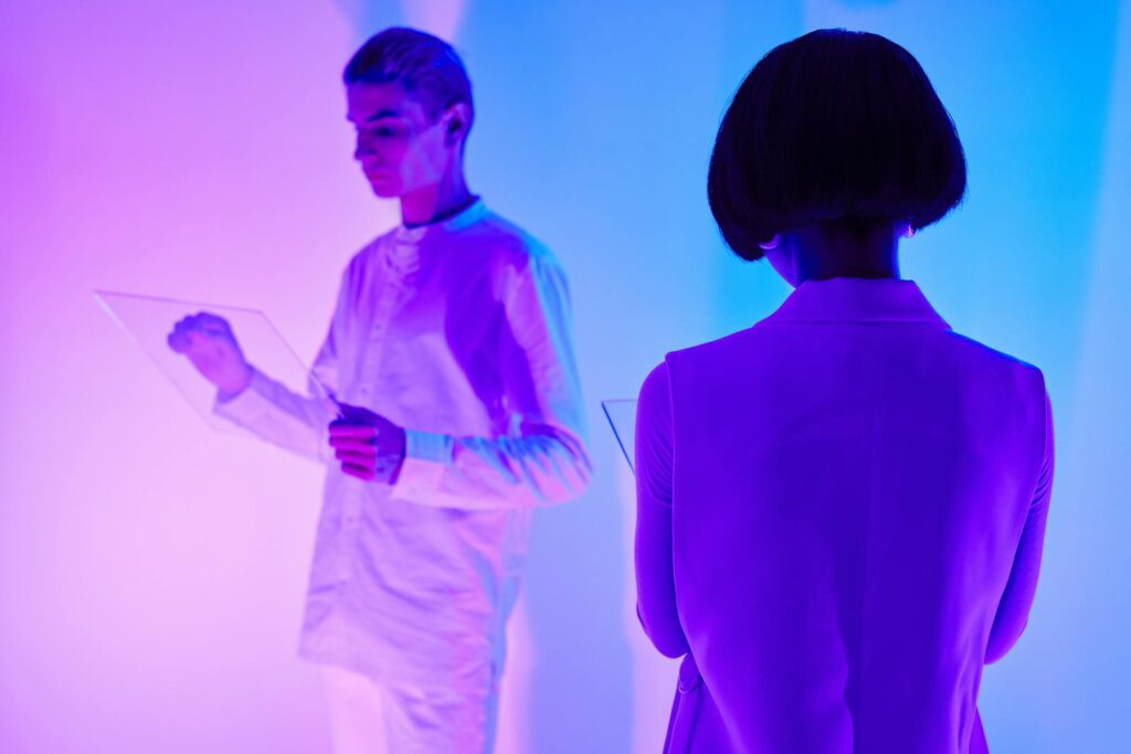 Two individuals interact with digital interfaces in a colorful futuristic setting.