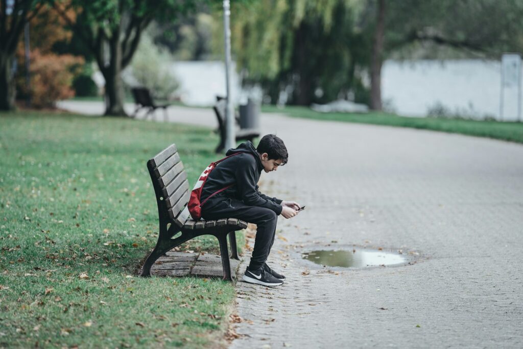 man in black jacket sitting on bench