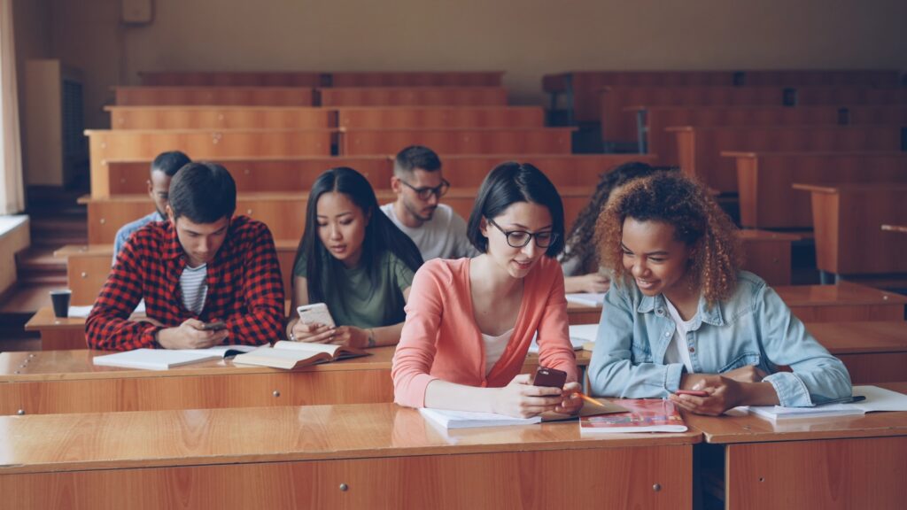How Schools Are Teaching New Teens to Outsmart Social Media and AI Students using phones in a lecture hall.