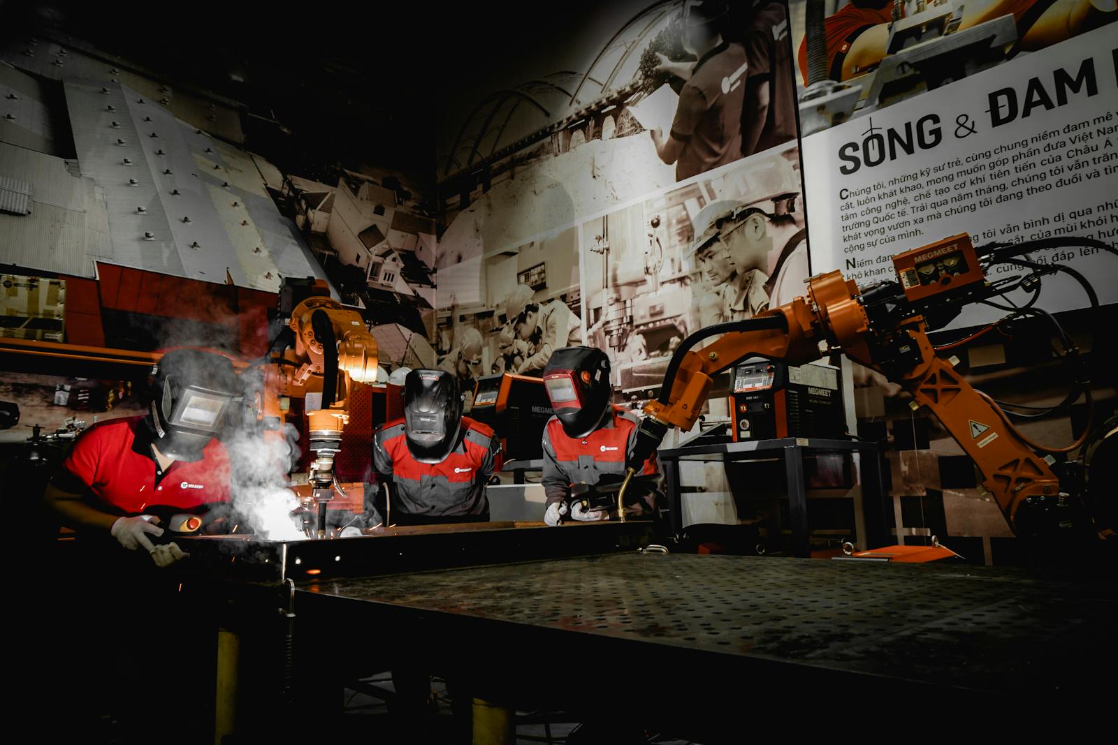 Three welders in protective gear working with robots in a high-tech industrial workshop.
