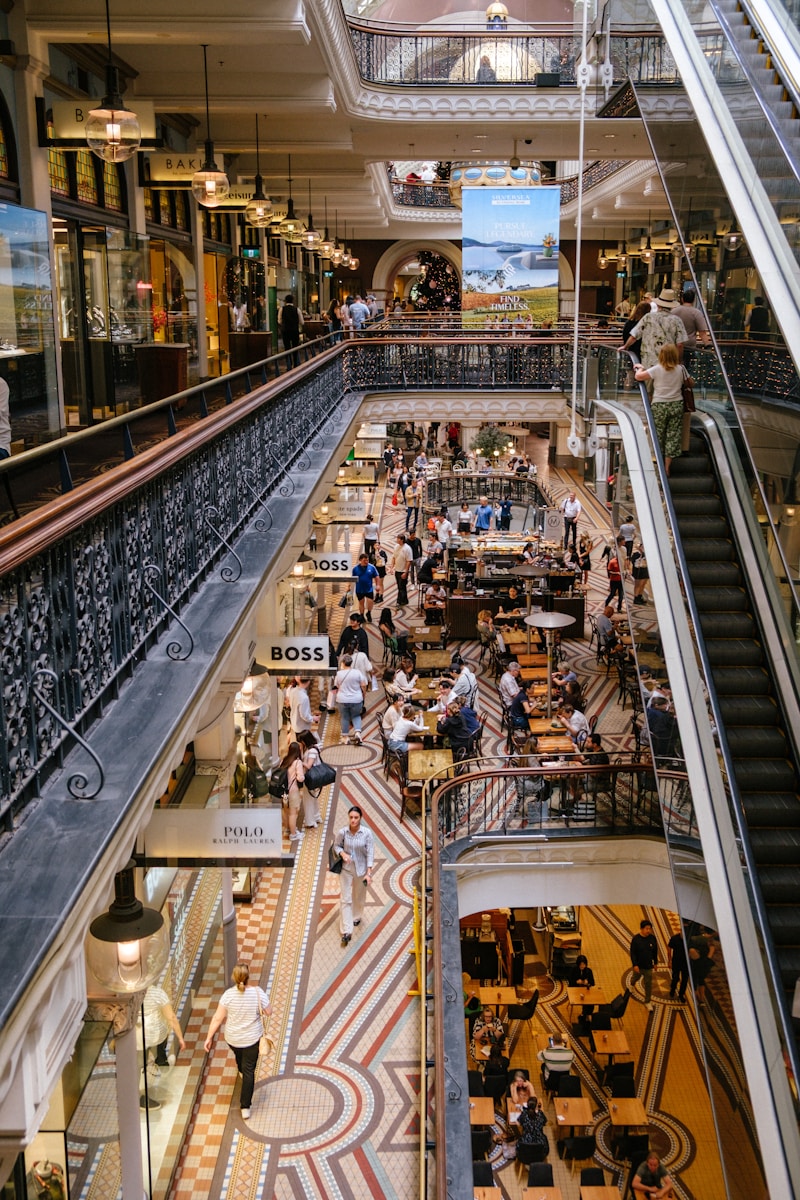 Why Tech Companies Want New AI Everywhere in Store and Shoppers Busy shopping arcade with escalators and people.