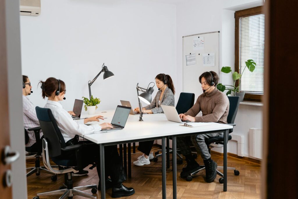 Team of professionals working in a call center using laptops and headsets in a modern office.