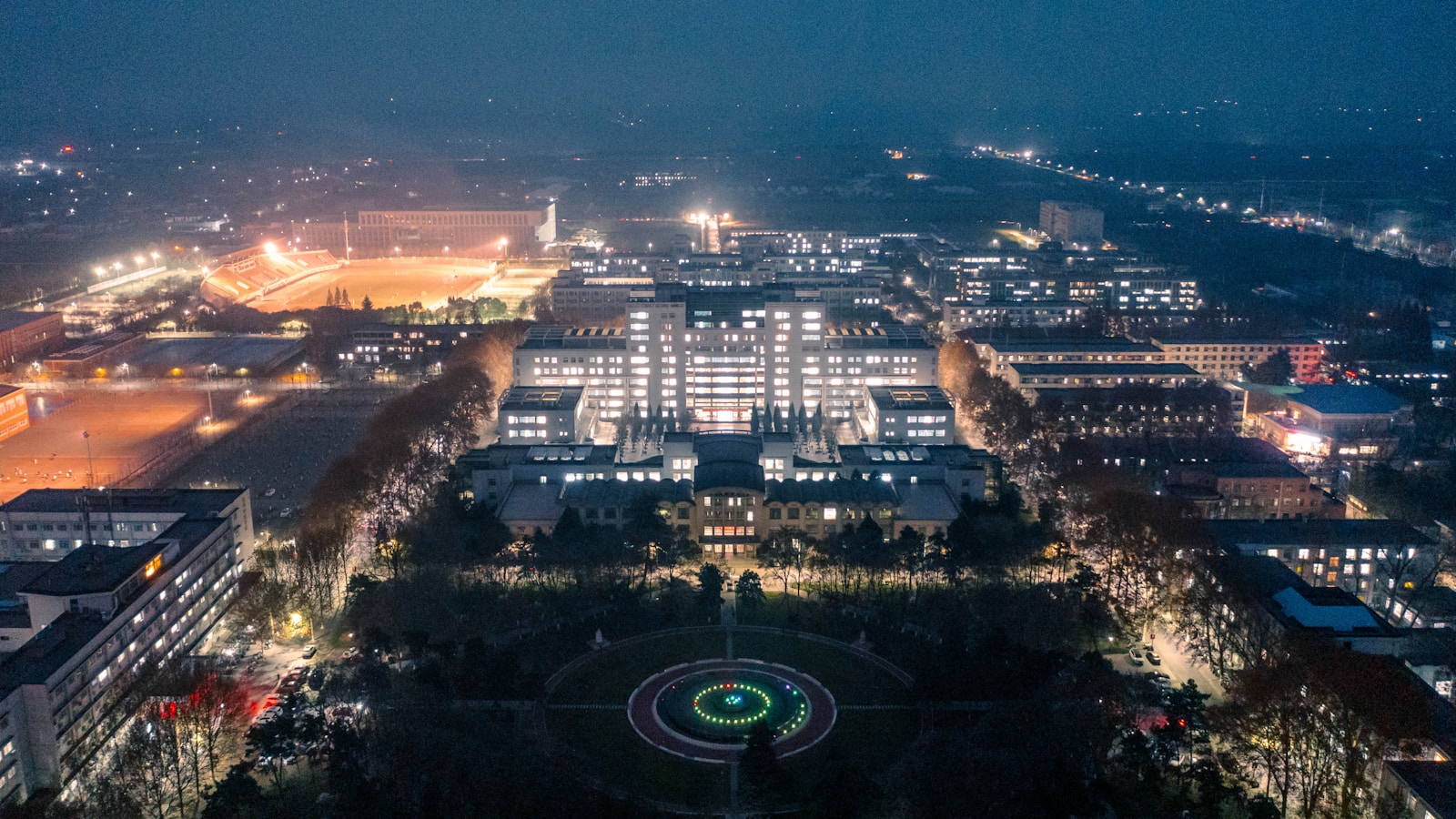 Modern university campus buildings at night with lights.