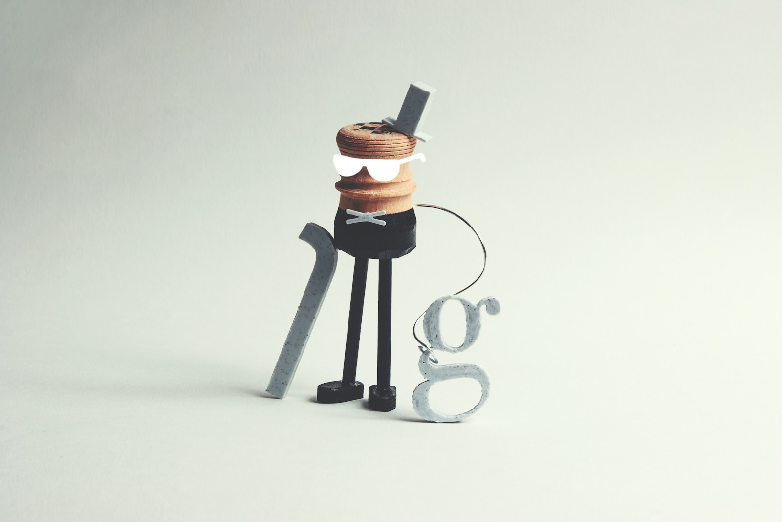A whimsical character with a cane and letter 'g' accessory.
