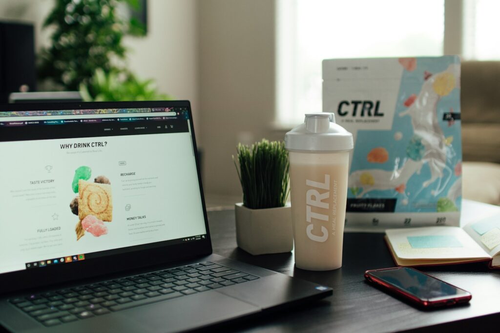 macbook pro beside white ceramic mug on brown wooden table