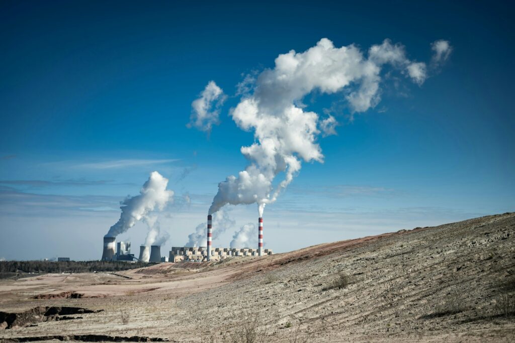 Industrial power plant emitting smoke under a clear blue sky.