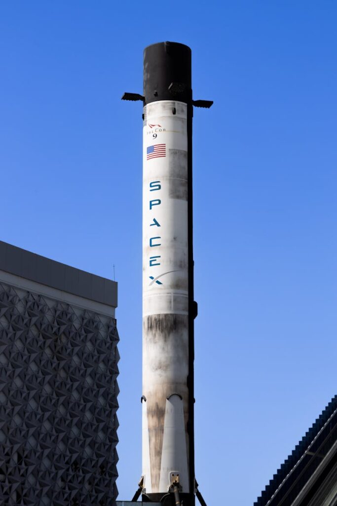 Vertical view of SpaceX rocket displayed in Dubai against clear blue sky.