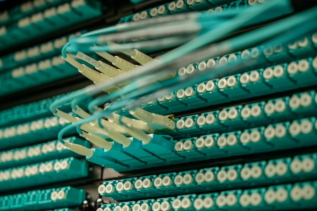 The AI Spending Boom Is Reshaping the Economy — and Creating New Shortages No One Expected Detailed view of fiber optic cables connected to a server rack, showcasing modern technology.
