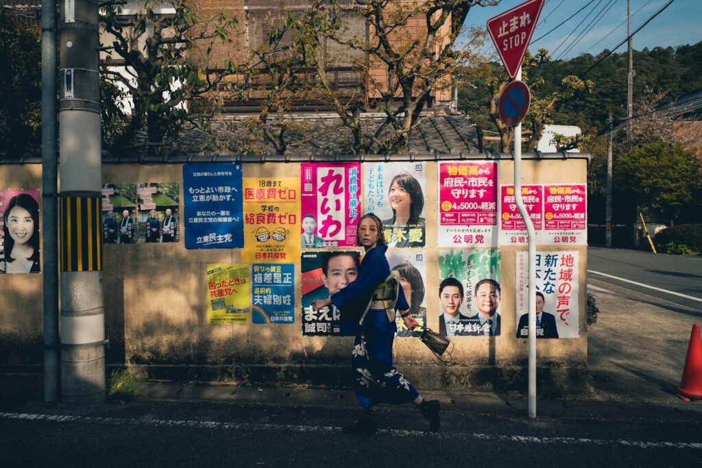 How AI Reshaping Japan’s New Elections and Redefining Political Power a man walking down a street past a wall covered in posters