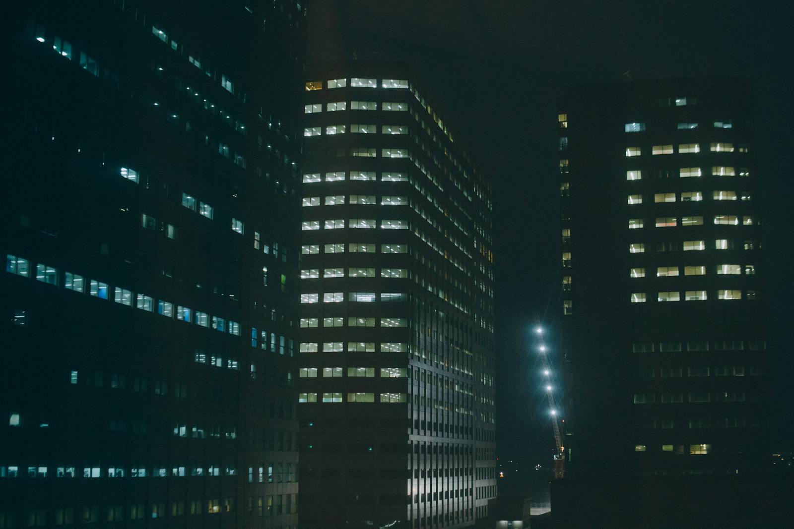 Night view of illuminated office buildings in a city, creating a mysterious urban atmosphere.