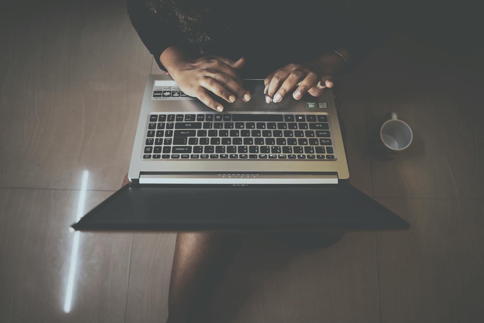Aerial shot of a person typing on a laptop with a nearby mug. Perfect for technology and lifestyle themes.
