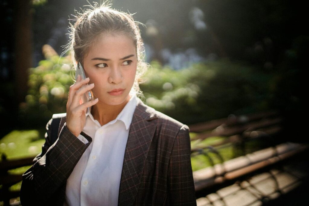 Businesswoman in formal attire having a phone conversation outside.