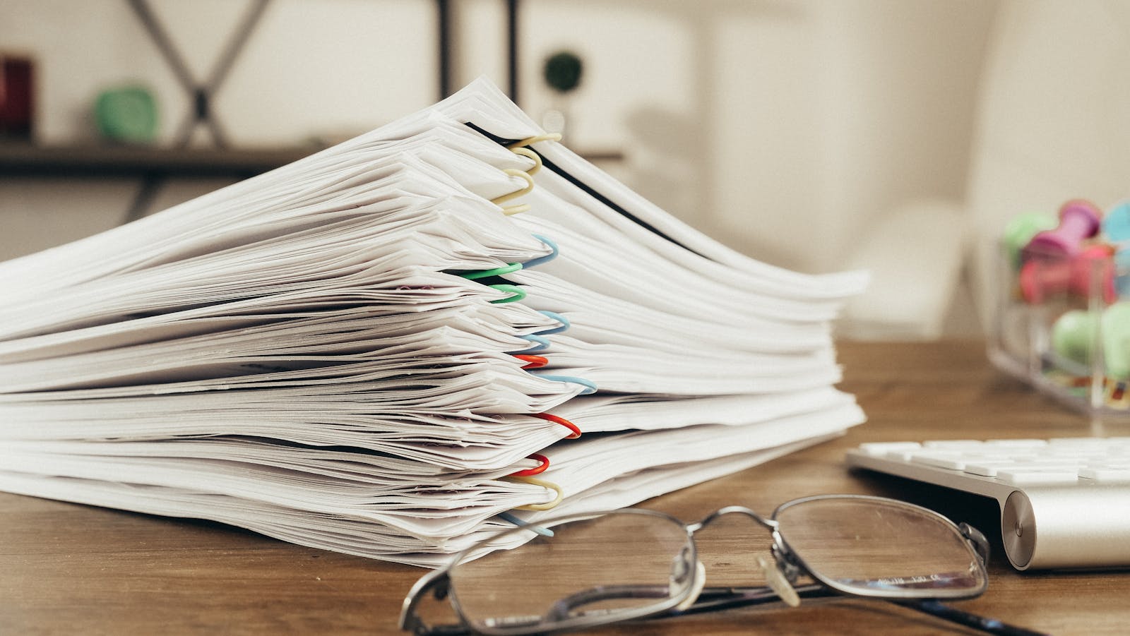 Inside the Trump Administration’s New AI Push on Technological Future Close-up of a stack of office papers on a desk with glasses, emphasizing organization.