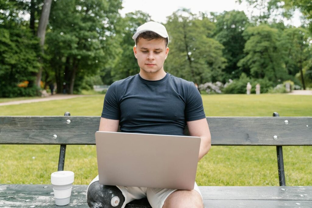 The Viral AI Post That Sparked a New Bigger Question Man in a park working on a laptop with a prosthetic leg, symbolizing accessibility.