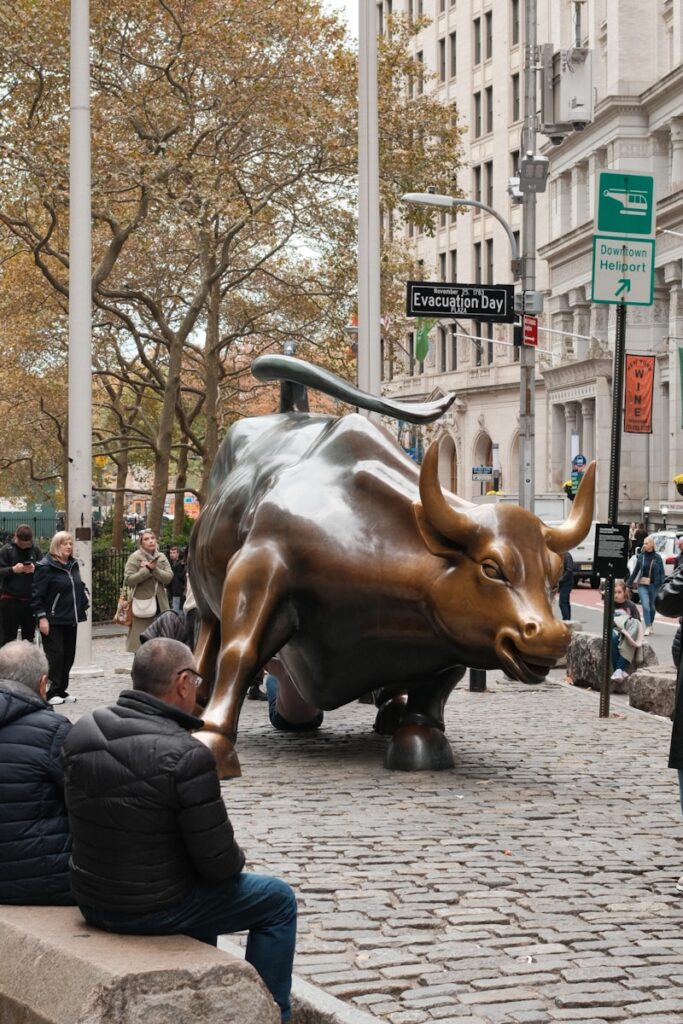 Charging bull statue on cobblestone street with onlookers