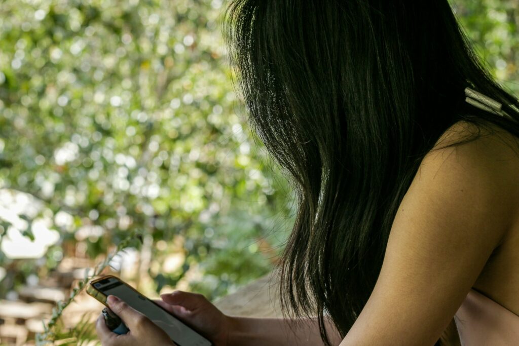 How AI and New Digital Tools Are Being Used to Control, Harass, and Silence Women a woman holding a cell phone in her hand