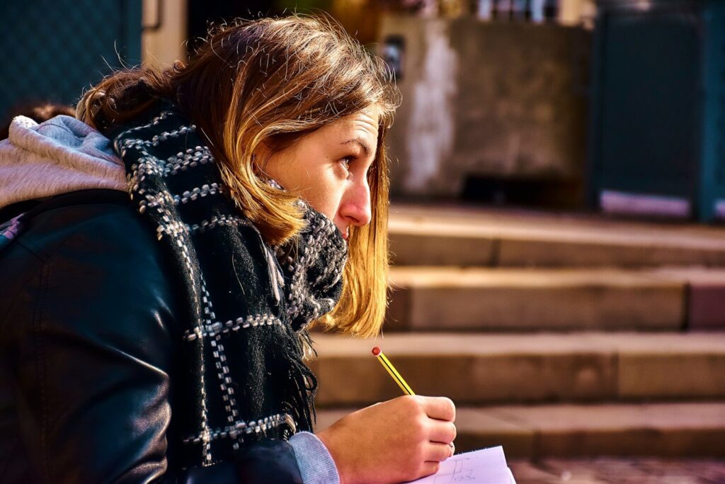 Why A.I. Literacy Becoming New Most Important Skill in Schools Woman writing on paper with a pencil outdoors