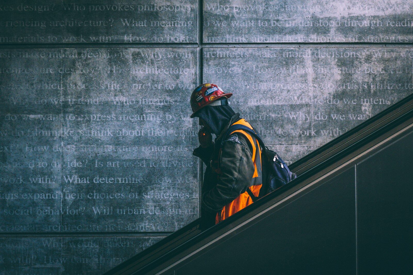 Why Tech Industry’s Fastest Revolution Is Meeting New Resistance a man wearing a hard hat and safety gear walking down an escalator