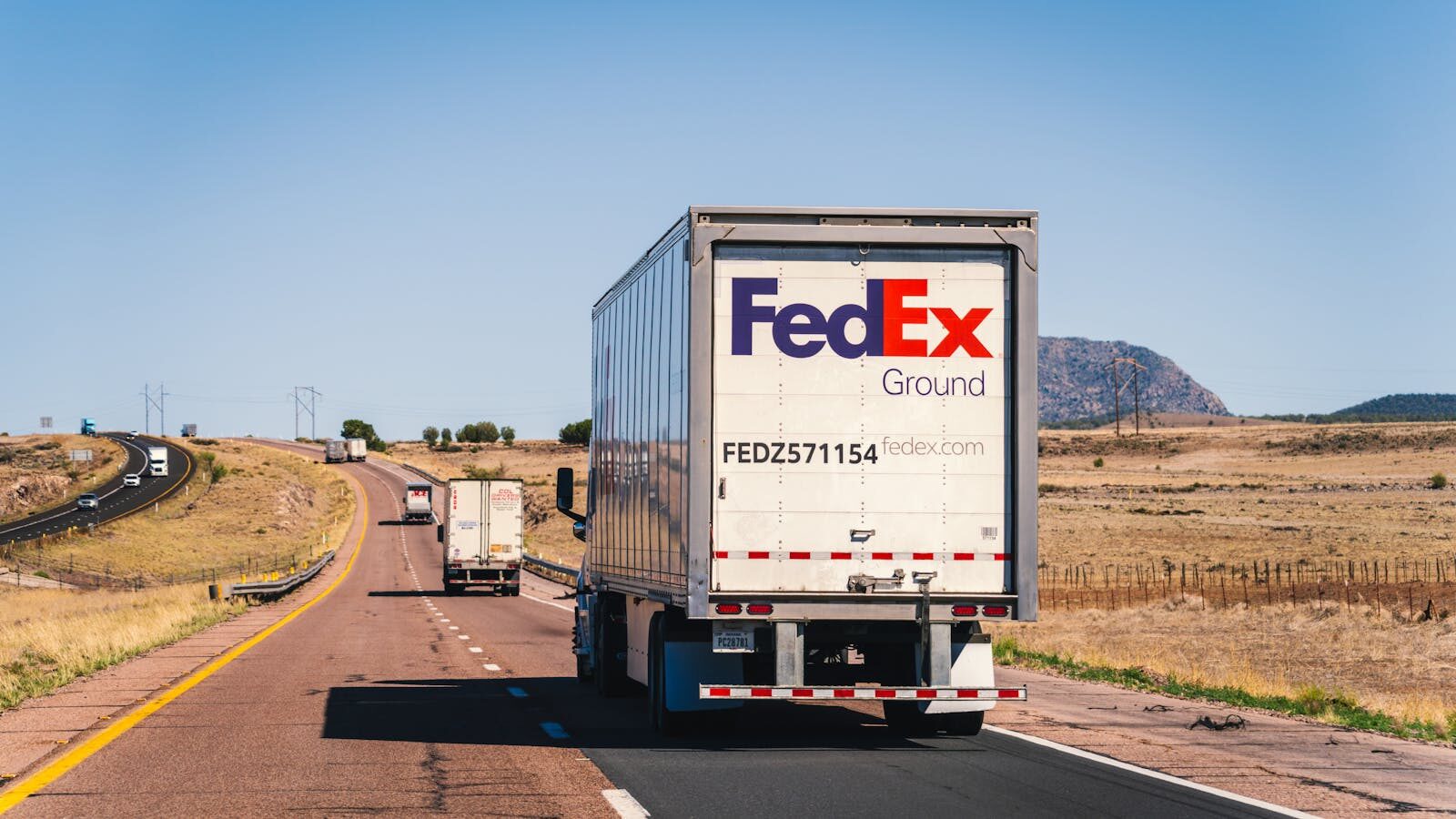 How Intelligent Agents Transform Global Logistics and New Future Work FedEx truck on a scenic desert highway in Arizona, showcasing transportation and logistics.