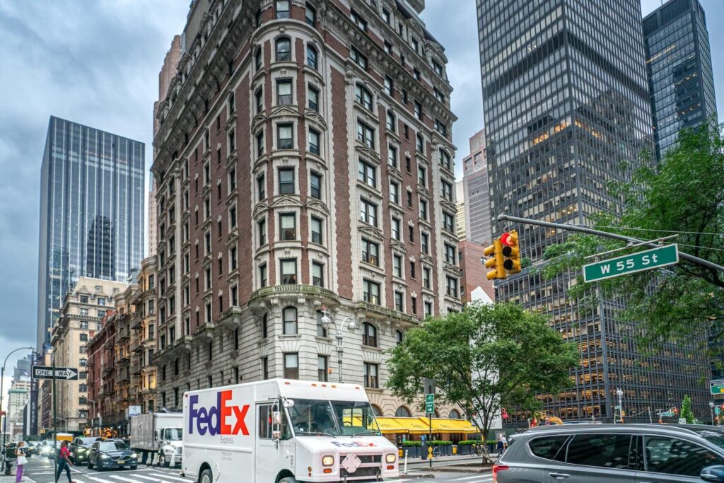 How Intelligent Agents Transform Global Logistics and New Future Work FedEx truck on a bustling street in New York City with skyscrapers and traffic, showcasing urban life.