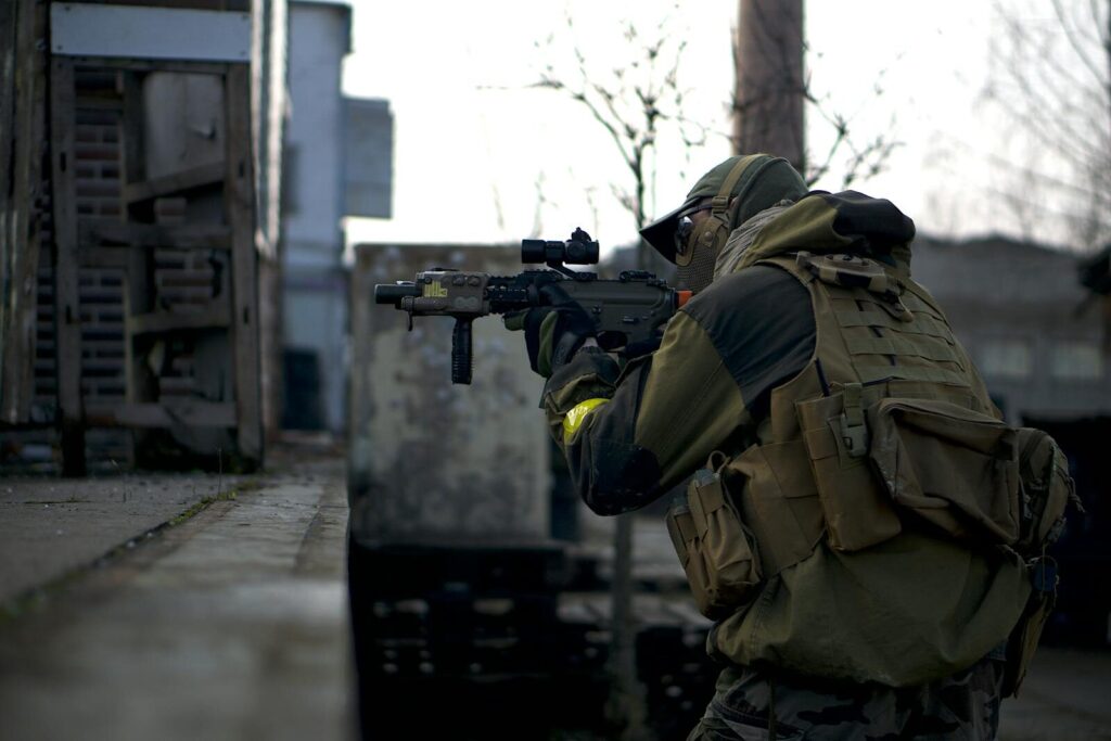 A soldier in camouflage with a rifle prepares in an urban environment, ready for action.