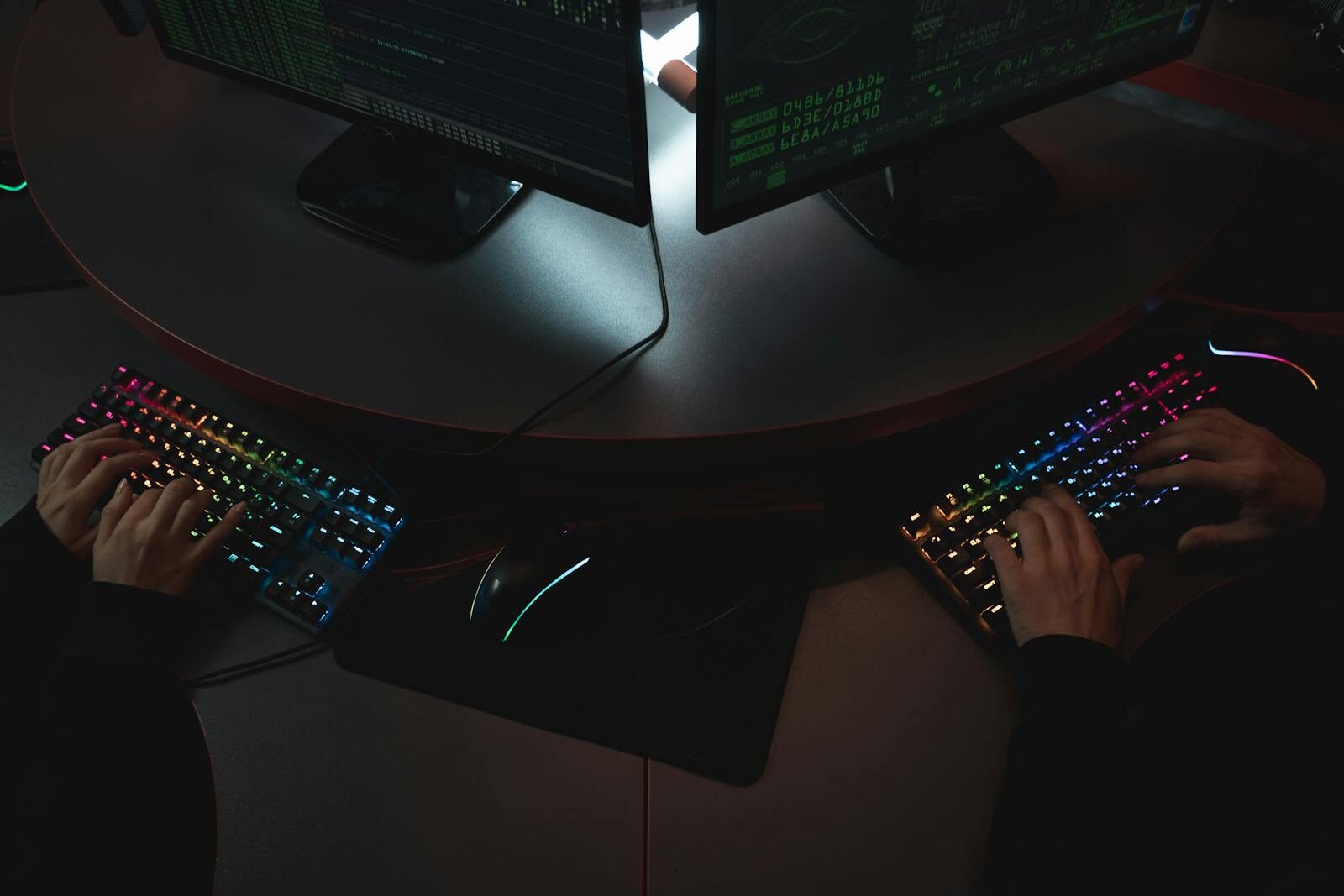 Why Anthropic Is Hiring New Experts to Prevent Dangerous Misuse Two people typing on RGB keyboards with code on screens, indicating a cybersecurity environment.
