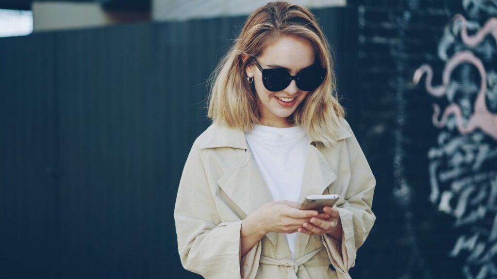The Endless New Conversation That Won’t Slow Down A young woman in sunglasses uses her smartphone.
