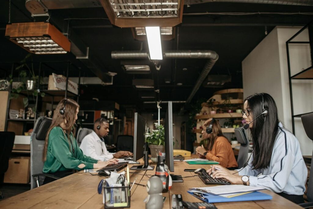 A mixed-gender team working at a call center desk, focusing on customer service tasks.