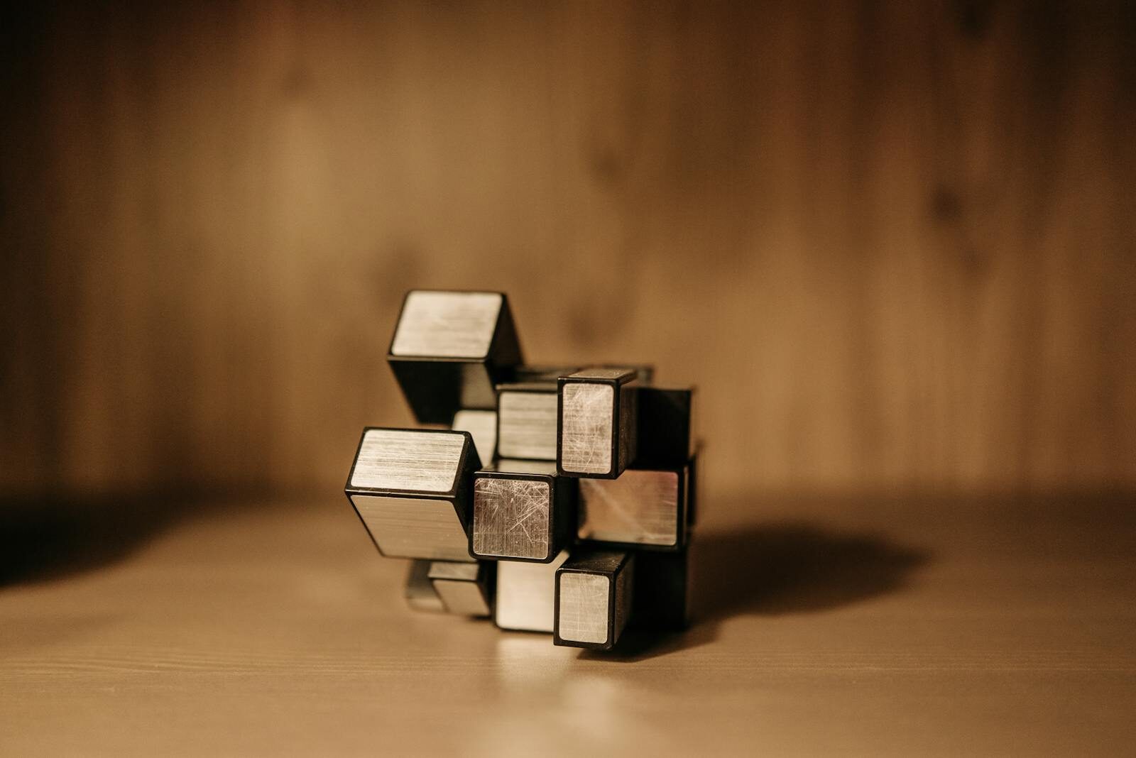 Close-up of a metal puzzle cube against a warm blurred background.